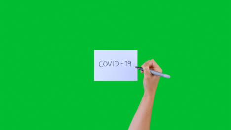Frau-Schreibt-Covid-19-Auf-Papier-Mit-Grünem-Bildschirm